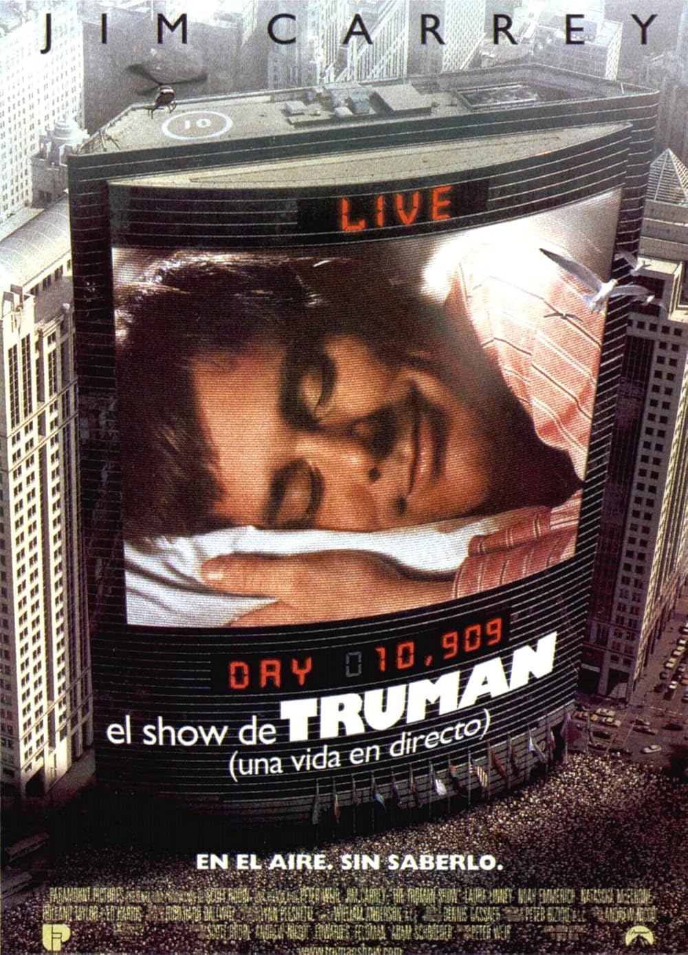 Paisaje urbano con una gran pantalla digital en un edificio que muestra a un hombre durmiendo, con la leyenda "EN VIVO, Día 10.909, el show de TRUMAN". 
